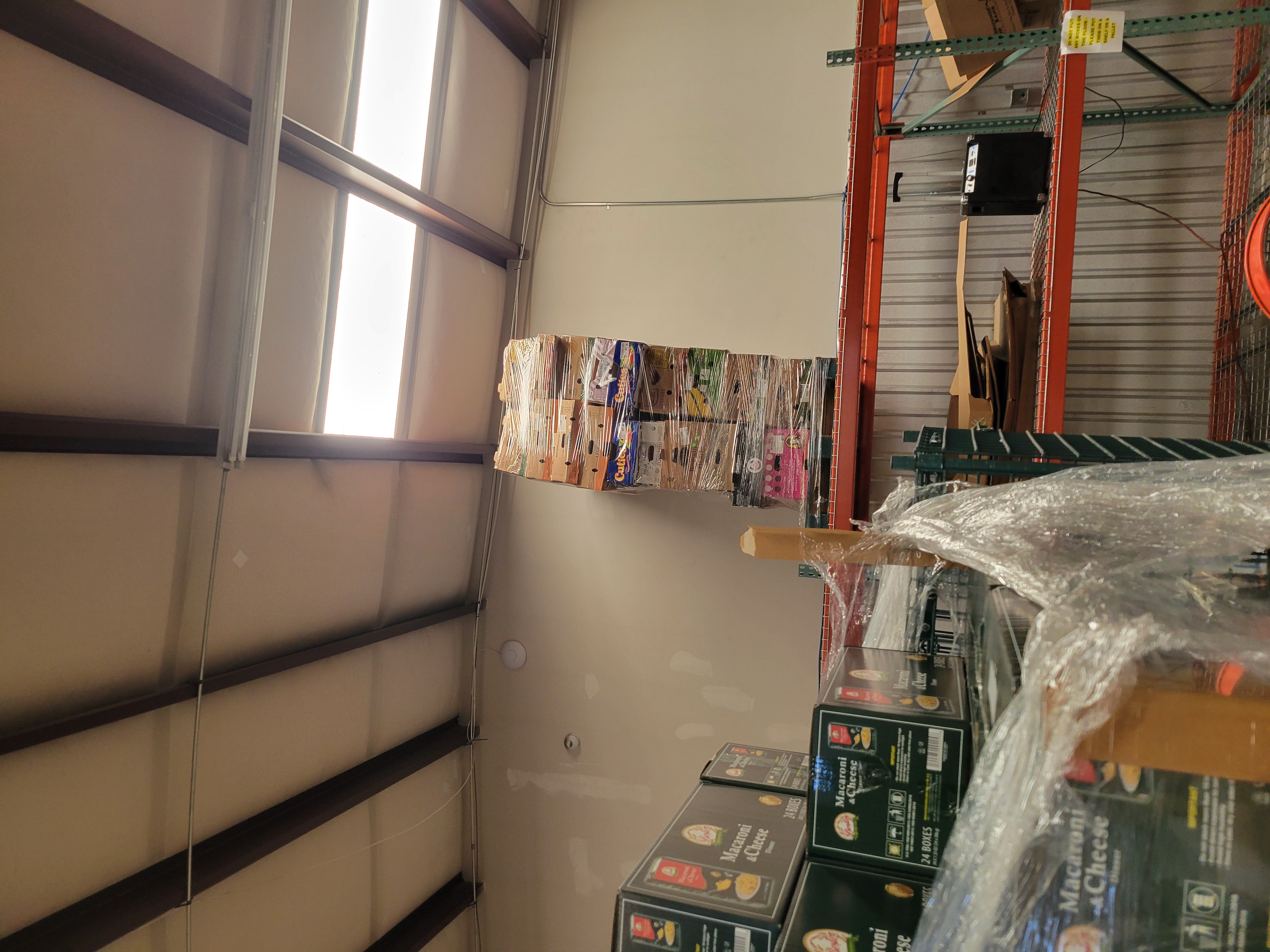 Various fruit boxes on a pallet wrapped in plastic wrap and placed on the top shelf.